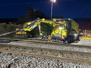 Vacuum excavator removing ballast beside railway track at night for safe rail infrastructure maintenance project